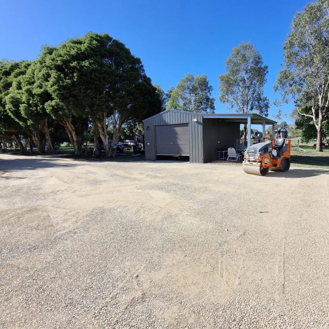 a parking area next to a shed with a roller parked on it